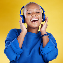 Image showing Music, headphones and black woman singing in studio isolated on a yellow background. Podcast, radio singer and happy African female streaming, enjoying and listening to audio, sound track or song.