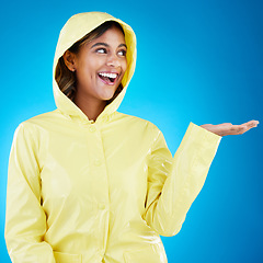 Image showing Hand, rain and happy woman in studio excited for weather, drop or storm while posing on gradient blue background. Smile feeling and girl enjoy rainfall, splash and winter season, cheerful or isolated