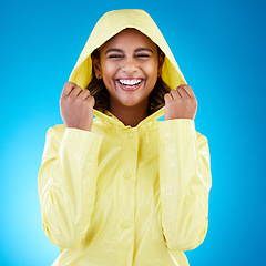 Image showing Cover, happy and portrait of a woman with a raincoat isolated on a blue background in a studio. Smile, laughing and girl wearing a jacket to protect from rain, the cold or bad weather on a backdrop