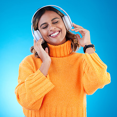 Image showing Music headphones, smile and woman in studio isolated on a blue background. Podcast, radio and happy Indian female with eyes closed streaming, listening and enjoying sound, audio or song with headset.