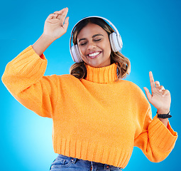 Image showing Music headphones, smile and woman dance in studio isolated on a blue background. Dancing, radio and happy Indian female with eyes closed streaming, listening and enjoying sound, audio podcast or song