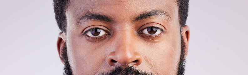 Image showing Black man, eyes and face portrait in studio for vision, focus and serious expression to stare. African male person on a grey background for eyesight, determination and awareness of unique identity