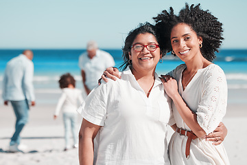 Image showing Portrait, nature with a mother and daughter on the beach during summer while their family play in the background. Love, smile or summer with a senior woman and adult child bonding outdoor together