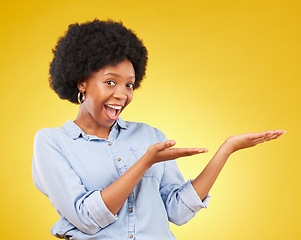 Image showing Space, portrait of a black woman in studio showing mockup for advertising or marketing. Happy, smile and face of African female model pointing to mock up for product placement by yellow background.