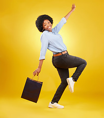 Image showing Bag, portrait and happy black woman shopping, excited and celebrating sale in studio on yellow background. Face, shopper and girl customer cheerful after boutique, retail or store discount isolated