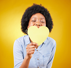 Image showing Paper, heart and happy with black woman in studio for romance, positive and emotion. Happiness, love shape and giving with female isolated on yellow background for date, feelings and affectionate