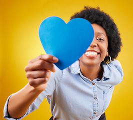 Image showing Paper, heart and happy with black woman in studio for romance, positive and emotion. Happiness, love shape and giving with female isolated on yellow background for date, feelings and affectionate