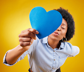 Image showing Paper, heart and kissing with black woman in studio for romance, positive and emotion. Happiness, love shape and giving with female isolated on yellow background for date, feelings and affectionate