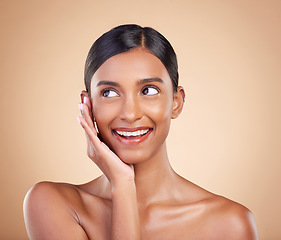 Image showing Thinking face, smile or makeup on happy woman in studio isolated on beige background for natural facial skincare. Hand, beauty or beautiful young Indian girl with luxury self care or glowing results