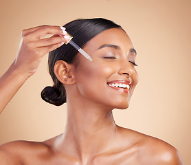 Image showing Happy woman, dropper and retinol on face for beauty, skincare or cosmetics against studio background. Female model with smile applying oil drop to skin for hydration, moisturizer or facial treatment