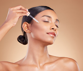 Image showing Woman, dropper and retinol on face for skincare beauty or cosmetics against a studio background. Beautiful female with pipette applying oil drop to skin for hydration, moisturizer or facial treatment