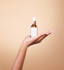 Image showing Hand, product and antiaging serum with a woman in studio on a beige background to promote skincare. Marketing, advertising and luxury with a female holding a bottle for the promotion of beauty