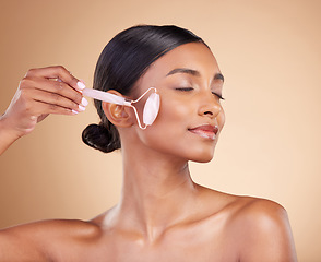 Image showing Woman, roller and face for skincare beauty, cosmetics or dermatology and anti aging against a studio background. Happy female model rolling skin for facial treatment, natural health and wellness