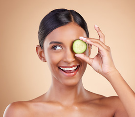 Image showing Smile, beauty or happy woman with cucumber for cleaning, detox and healthy facial treatment routine. Wellness, face or Indian girl with skincare nutrition or cosmetics isolated on studio background