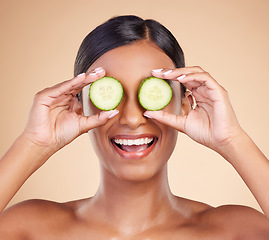 Image showing Woman, face and cucumber for natural skincare, beauty and nutrition cosmetics against a studio background. Happy female holding vegetables with smile for healthy organic facial, diet or spa treatment