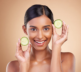 Image showing Portrait, beauty and cucumber with a woman in studio on a beige background to promote natural skincare. Face, fruit and organic with an attractive young female posing for cosmetics or luxury wellness