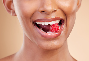 Image showing Woman, mouth and raspberry for skincare nutrition, dermatology or diet health plan against a studio background. Female lips with fruit for natural organic food, self care or eat for healthy wellness