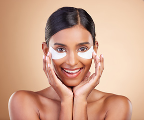 Image showing Beauty, eye patch and portrait of a woman in studio for skincare, dermatology and cosmetics. Happy Indian female model with smile and collagen mask for self care moisture facial on brown background