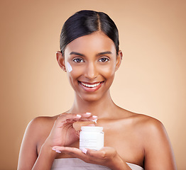 Image showing Portrait, product and cream with a model woman in studio on a beige background for beauty or skincare. Face, advertising and lotion with an attractive young female holding a cosmetics container