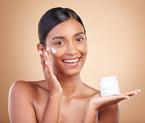 Image showing Portrait, product and lotion with a woman in studio on a beige background for beauty or skincare. Face, advertising and moisturizer with an attractive young female model holding a cosmetics container