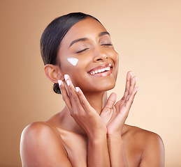 Image showing Woman, face and skincare moisturizer cream for beauty cosmetics or self care against studio background. Happy female model smile applying lotion, creme or product in satisfaction for cosmetic facial