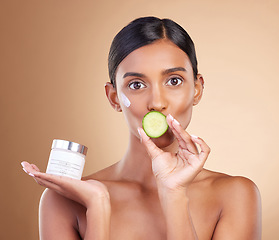 Image showing Woman, moisturizer cream and cucumber for natural skincare, beauty and nutrition against studio background. Portrait of female holding vegetable, creme or lotion for healthy organic diet or wellness