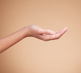 Image showing Hands, palm and product placement for mockup in studio isolated on a brown background. Skincare, dermatology and woman model with hand out for marketing, advertising or branding space for mock up.