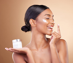 Image showing Woman, face and smile with moisturizer cream for beauty skincare cosmetics, self love or care against a studio background. Happy female smiling for lotion, moisturizing creme or facial treatment