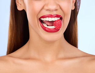 Image showing Beauty, health and raspberry with mouth of woman in studio for nutrition, diet or detox. Cosmetics, natural and self care with girl model eating fruit on blue background for wellness, organic or glow