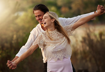 Image showing Happy, love and couple laugh in nature at sunset for romance, bonding and quality time together. Summer, dating and man and woman holding hands on holiday, honeymoon vacation and relax on weekend