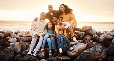 Image showing Happy family, parents and children in beach portrait with excited face, sitting or relax with grandparents on rocks. Woman, man and kids by ocean for love, care and bonding on holiday by sunset sky