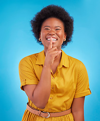 Image showing Portrait, smile and secret with a black woman in studio on a blue background standing finger on lips. Gossip, whisper and mystery withan attractive young female making a hand gesture emoji of privacy