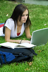 Image showing Cute teen girl laying down on the grass studying