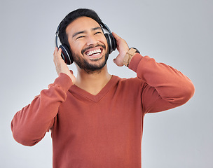 Image showing Happy asian man, headphones and music in studio with streaming, audio or web subscription by background. Student guy, listening and laughing with comic podcast, standup comedy album or hip hop single