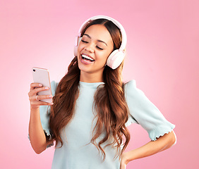 Image showing Phone, music headphones and woman singing in studio isolated on a pink background. Cellphone, radio singer and happy female with mobile streaming, laughing and listening to audio, sound or podcast.