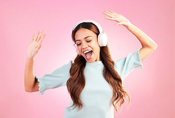 Image showing Music headphones, dancing and woman singing in studio isolated on a pink background. Singer, radio dance and happy mixed race female streaming, enjoying and listening to audio, sound track or podcast