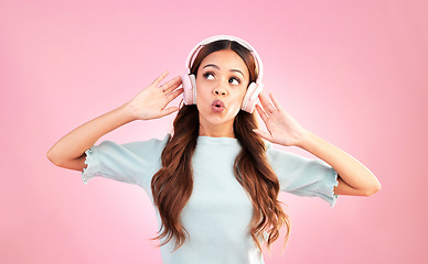 Image showing Music headphones, singing and woman whistle in studio isolated on a pink background. Singer, thinking and mixed race female streaming, enjoying and listening to audio, sound track or radio podcast.