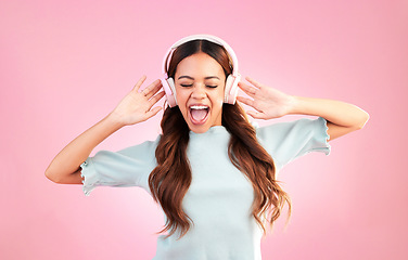 Image showing Music headphones, singing and woman dance in studio isolated on a pink background. Singer, dancing and happy mixed race female streaming, enjoying and listening to audio, sound track or radio podcast