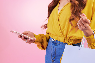 Image showing Phone, shopping bag and woman hands isolated on pink background for online shopping, ecommerce and retail. Fashion person on mobile app, cellphone or smartphone for discount, sale or promo in studio