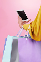 Image showing Phone screen, shopping bag and hands of woman isolated on pink background online shopping, ecommerce and retail. Fashion person on mobile app, cellphone or smartphone for mockup space in studio