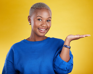 Image showing Portrait, smile and black woman with product placement palm in studio isolated on a yellow background. Mockup face, happy and African female with hand for advertising, marketing or branding space.