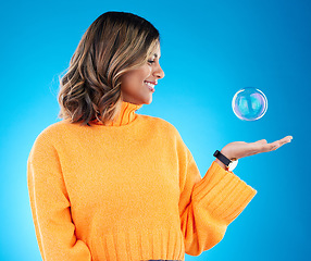 Image showing Happy, smile and bubble with indian woman in studio for soap, positive and satisfaction. Magic, creative and holding with female isolated on blue background for bright, cute and entertainment