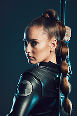 Image showing Woman, warrior and vigilante in cosplay with sword ready for battle, war or game against a dark studio background. Portrait of serious female in black superhero costume with blade for halloween