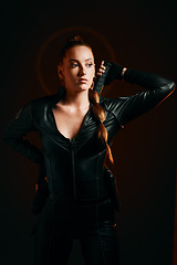 Image showing Woman, warrior and costume of vigilante in cosplay ready for battle, war or game against a dark studio background. Female in black leather uniform with sword and guns for halloween or hunger games