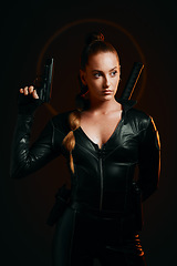 Image showing Serious woman, warrior and gun in studio for action, fight and safety from danger on dark background. Strong female assassin or agent in scifi leather cosplay costume with weapon to fight or guard