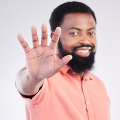 Image showing Black man, hand sign and stop in studio portrait with smile, icon and communication by background. Young african model, signal or symbol for opinion, protest palm and warning with confident choice