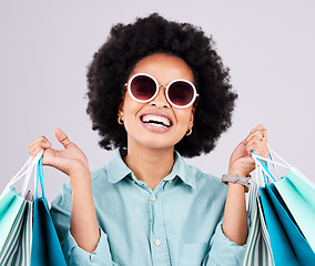 Image showing Shopping bag, retail glasses and happy black woman with luxury sales product, designer fashion deal or mall store present. Commerce market, discount gift and studio customer face on gray background