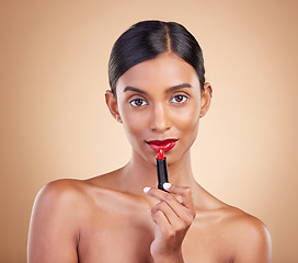 Image showing Indian woman, lipstick product and studio portrait for beauty, wellness or skincare by brown background. Asian model, girl and red makeup on lips with natural glow, self care or cosmetology for youth