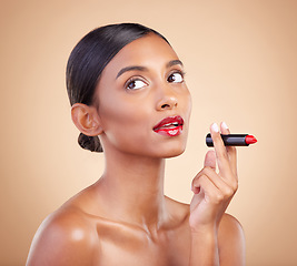 Image showing Beauty, red lipstick and makeup on a woman in studio for cosmetics, skin glow and shine product. Indian female model thinking on beige background for skincare, facial self care and lips with color