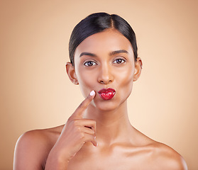 Image showing Beauty, red lipstick and makeup portrait of a woman in studio for cosmetics, skin glow and shine. Indian female model with finger on face or kiss on beige background for self care and lips with color